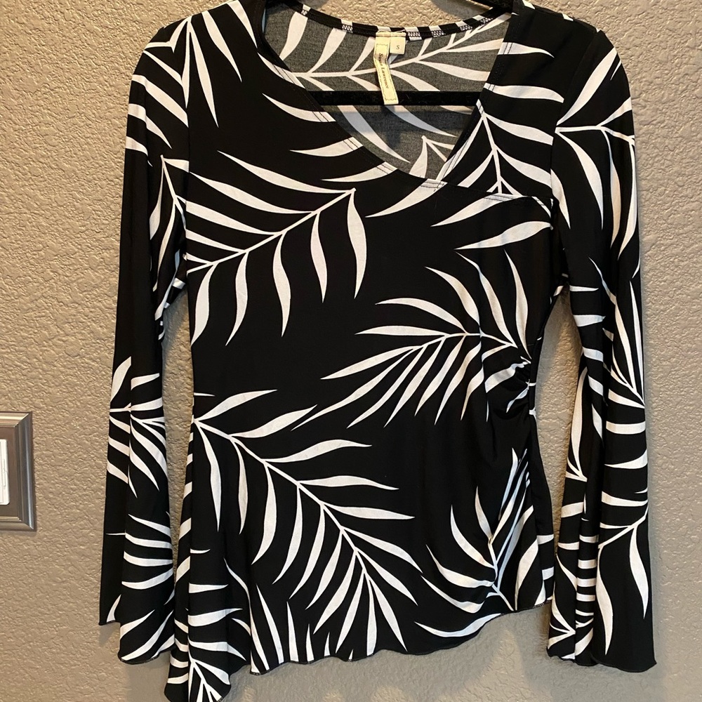 Women’s black/white floral long sleeve top. Asymmetrical design bell sleeves.